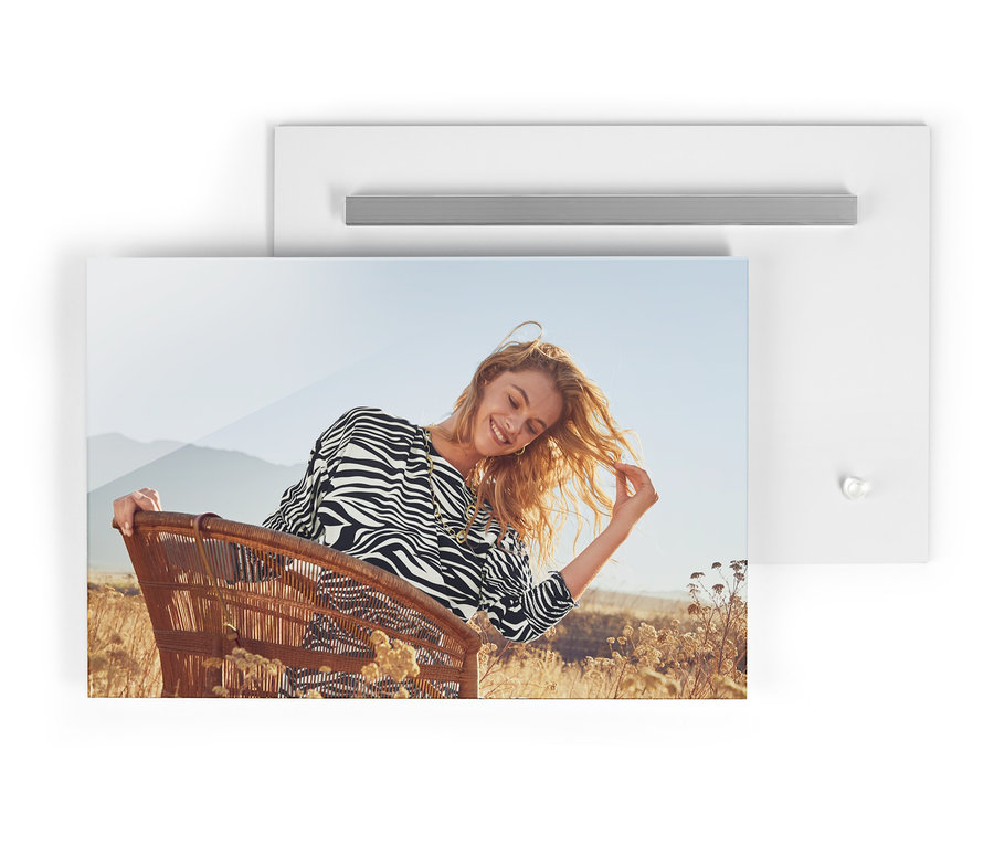 Das Foto zeigt eine Frau, die in einem Korbsessel in einem Midi-Kleid im Zebra-Dessin sitzt, mit einer Umhängetasche und einer Kette und Creolen »Schillerndes Afrika«.