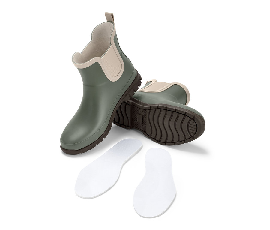 Grüne Gummistiefelette und zwei weiße Schuheinlagen auf weißem Hintergrund.
