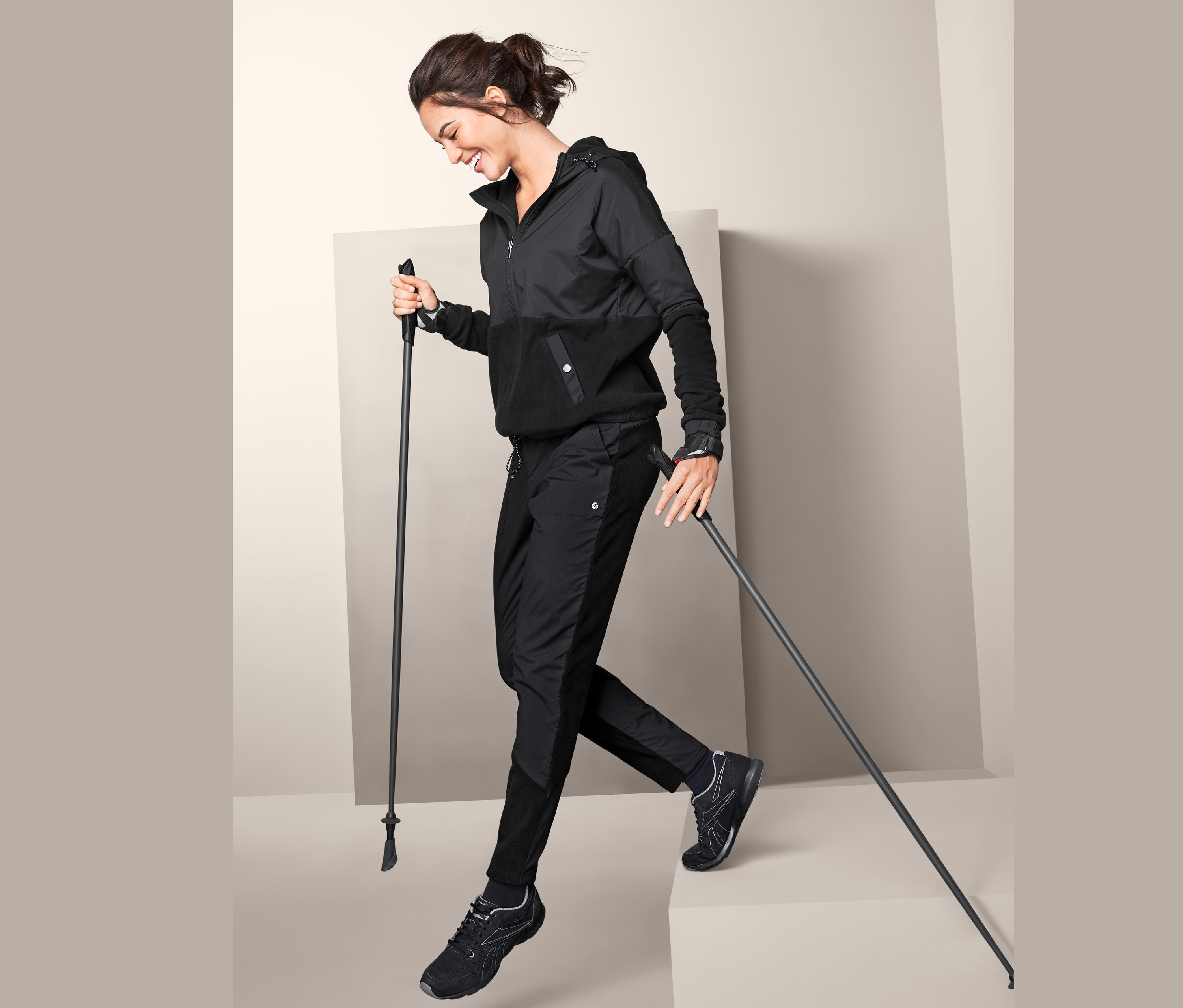 Frau geht mit Stöcken in schwarzer Hybrid-Fleecehose.
