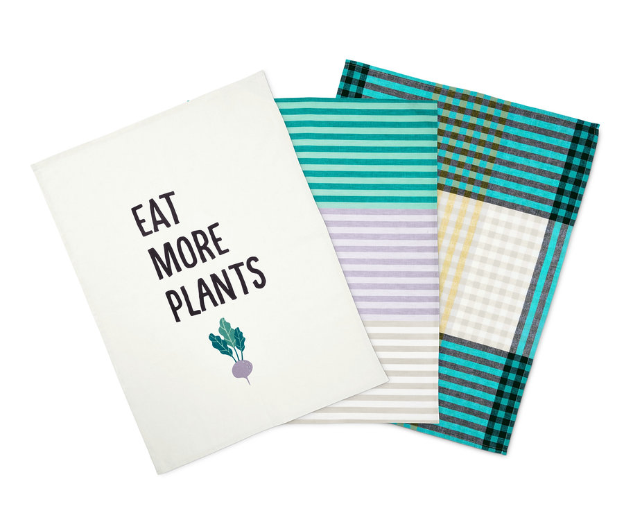Drei Geschirrtücher: ein weißes mit dem Aufdruck "Eat More Plants", ein gestreiftes und ein kariertes.