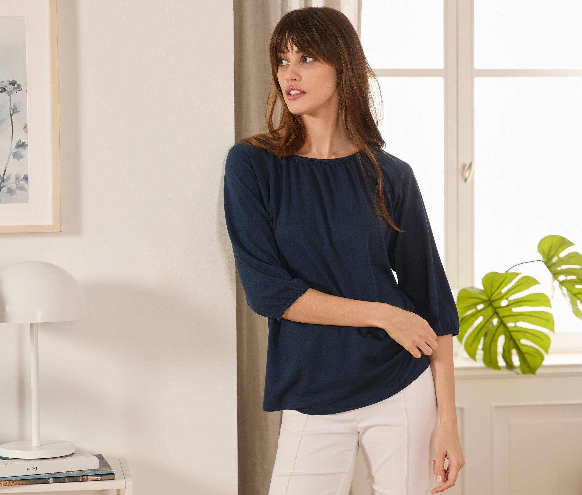 Frau posiert in dunkelblauem Shirt mit 3/4-Arm.