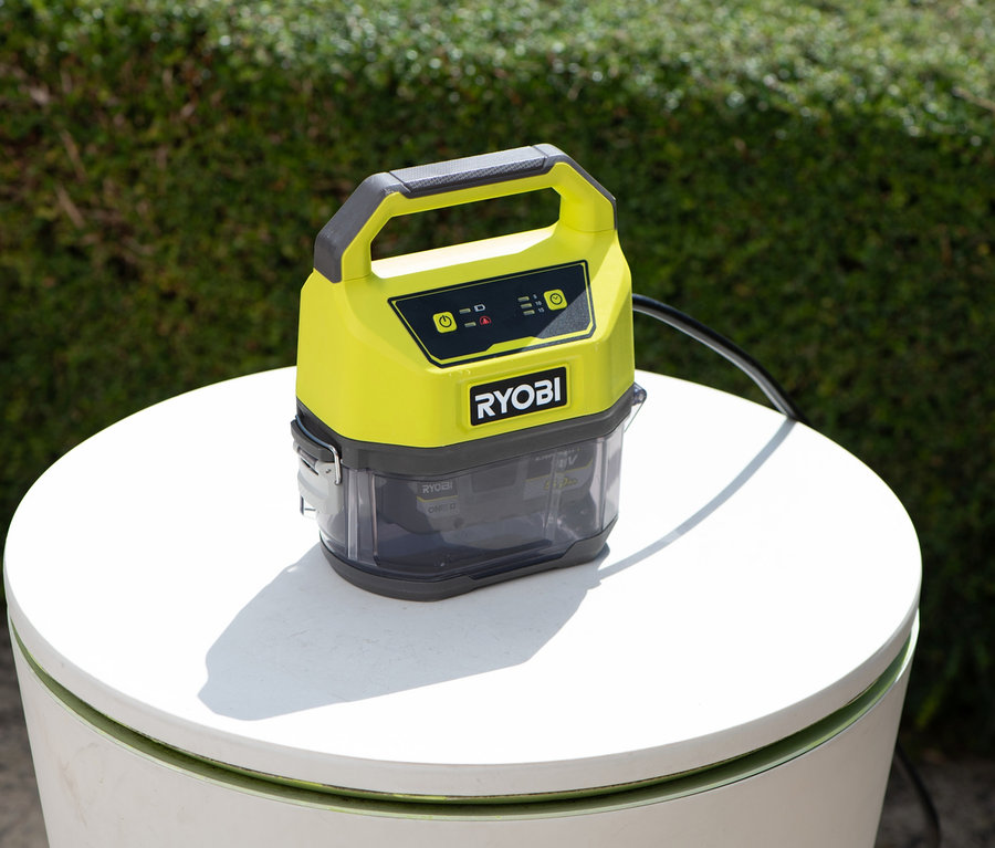 Gelbgraue RYOBI 18 V One+ Akku-Tauchpumpe ohne Akku und Ladegerät auf einem weißen runden Tisch.