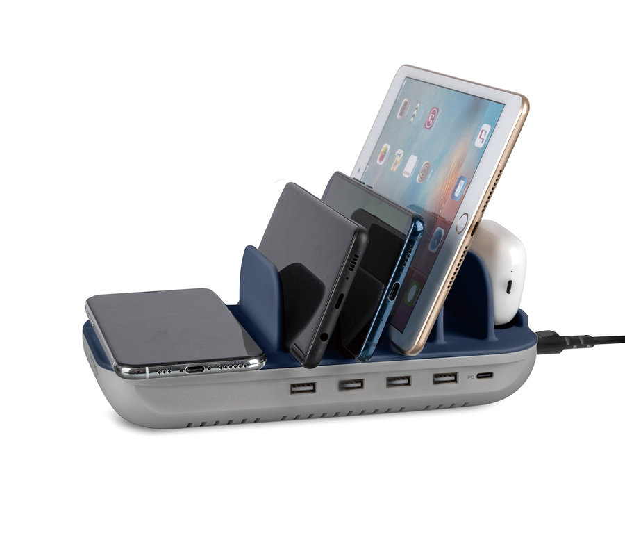 Auf einer grauen Ladestation mit blauen Fächern liegen ein Tablet, drei Handys und Kopfhörer. Multiport-Ladestation mit kabellosem Qi-Ladepad 63 W.