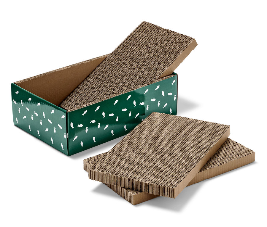 Eine grüne Katzen-Kratzbox mit weißen Fischen und zwei Stapel aus Karton-Kratzmatten.