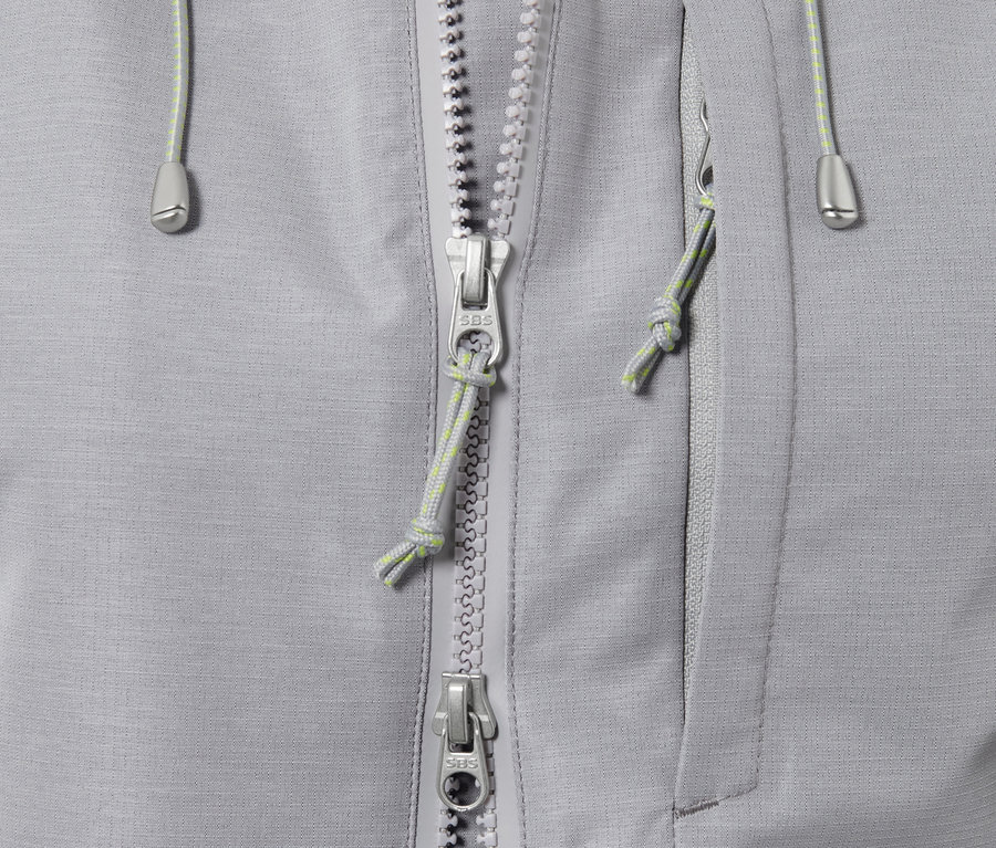 Detailansicht einer grauen Funktions-Outdoorjacke mit Reißverschluss und Tasche.