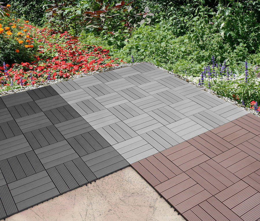 Quadratische 30 x 30 cm WPC Terrassenfliesen in Dunkelgrau und Braun sind auf einer Außenterrasse zu einem Muster angeordnet.