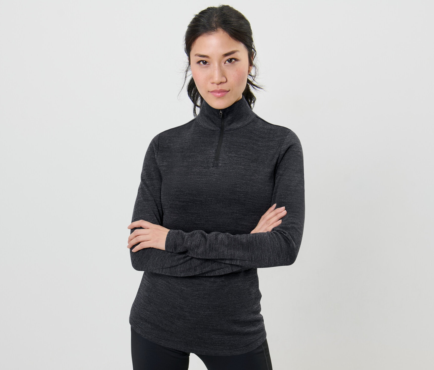 Frau posiert mit verschränkten Armen in einem Funktionsshirt mit RWS-zertifizierter Wolle.