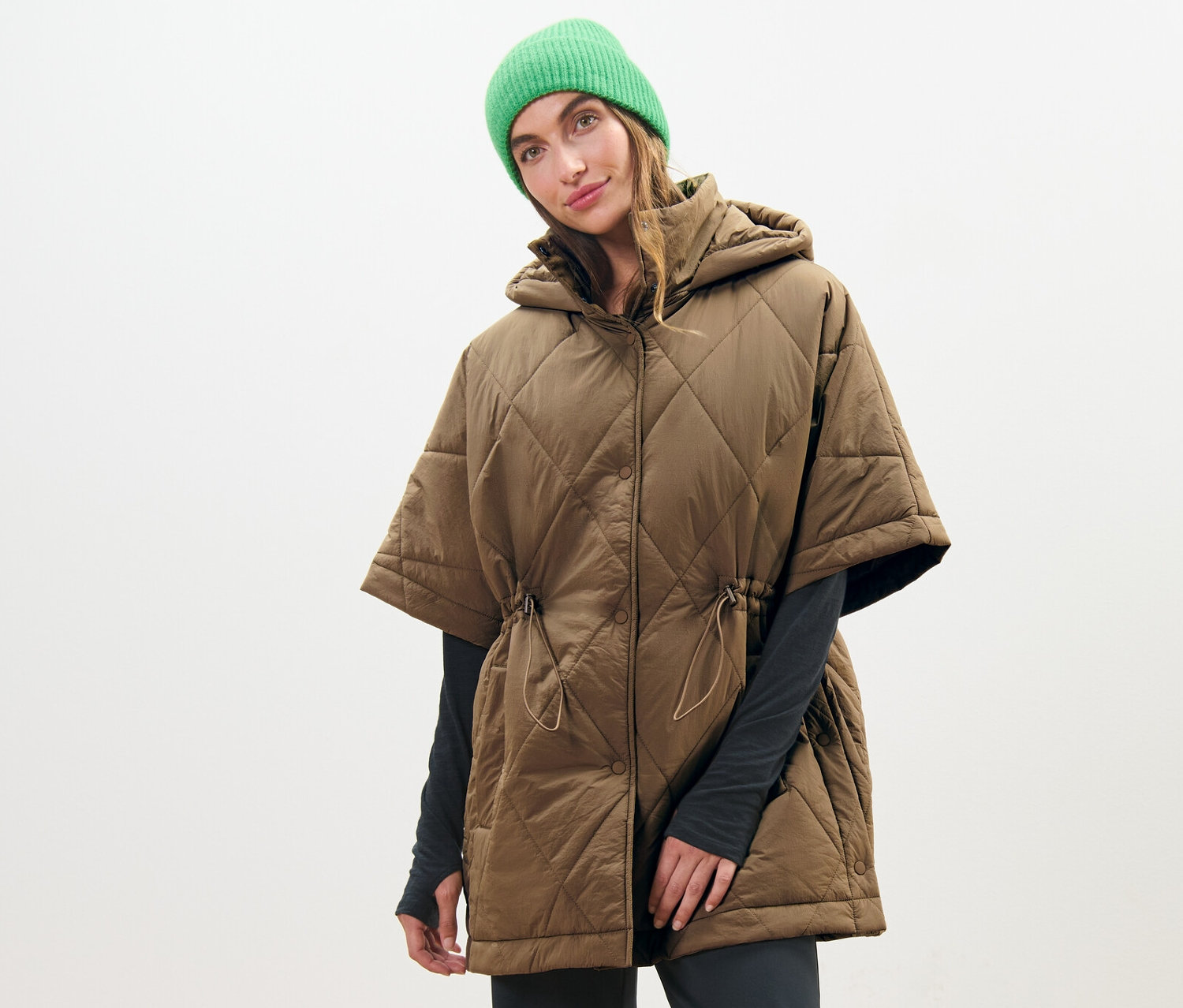 Frau trägt Kapuzen-Stepp-Poncho und grüne Mütze.
