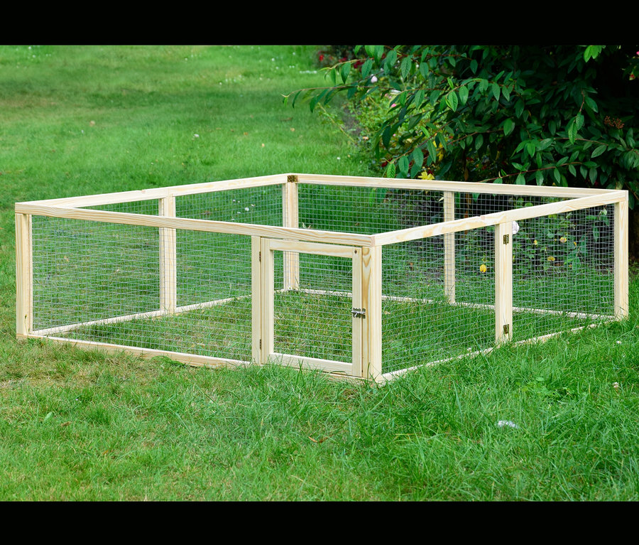 Ein rechteckiges, hölzernes Dobar Freilaufgehege mit Gitter steht auf einer Wiese.