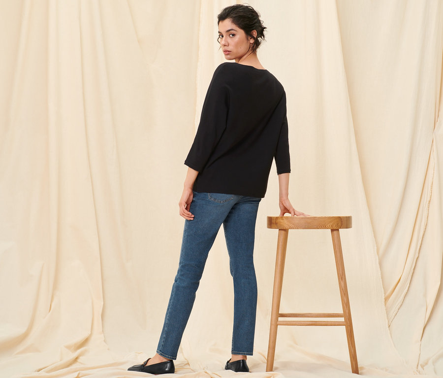 Frau posiert in Feinstrickpullover, schwarz, Slim-Denim »Fit Emma«, midblue denim und Leder-Loafern.