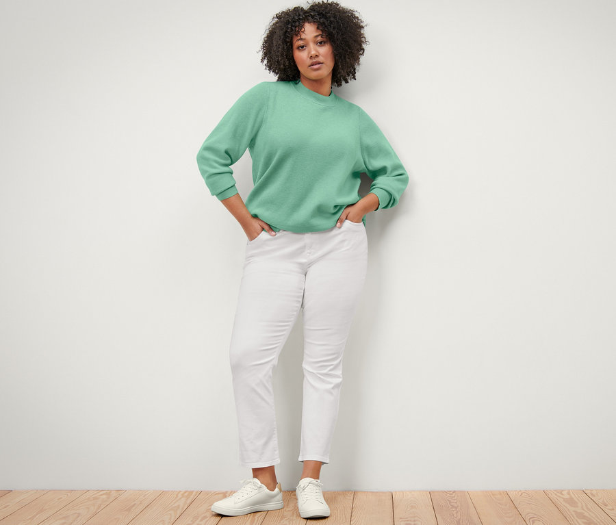 Frau posiert in einem Pullover und einer hellen »Emma« Jeans.