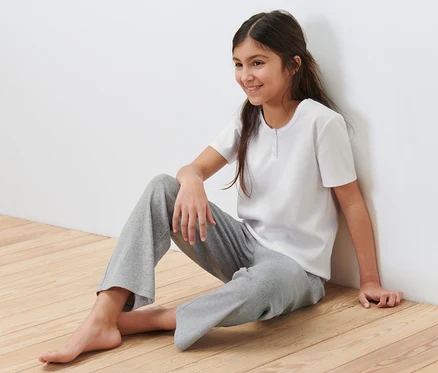 Ein Mädchen sitzt auf dem Boden und trägt einen Kinder-Ripp-Pyjama.