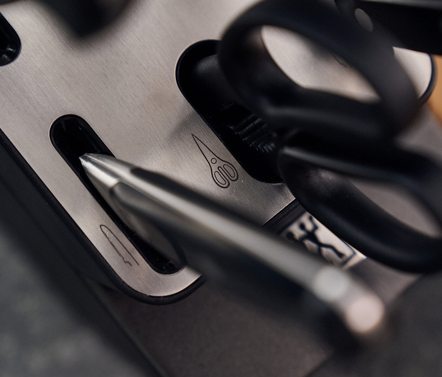 Detailansicht eines ZWILLING PRO Messerblocks mit silbernen Messern und einer schwarzen Schere.