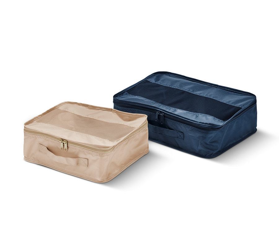 Zwei Reiseordnungstaschen, eine beige und eine marineblaue, liegen auf einem weißen Hintergrund.
