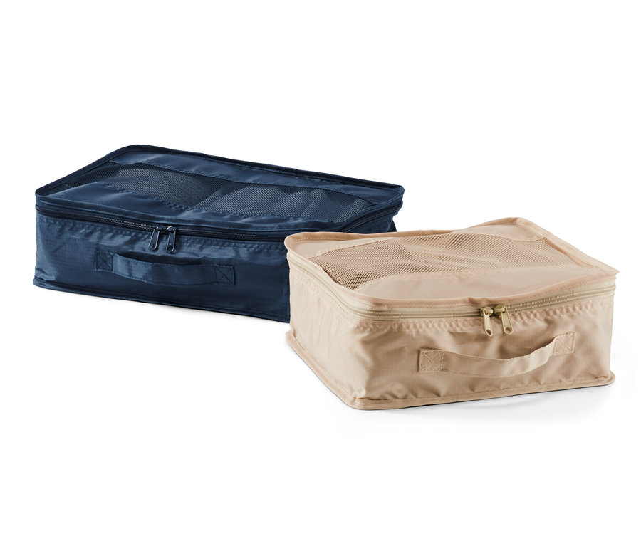 Zwei Reiseordnungstaschen, eine dunkelblaue und eine beige, liegen nebeneinander.