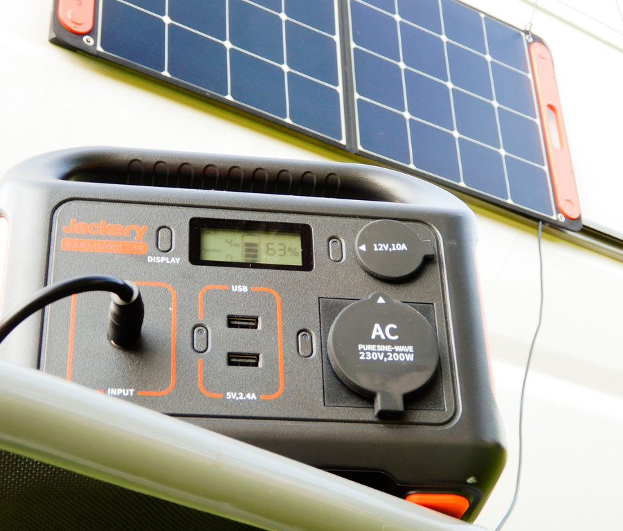 Ein schwarzes, tragbares Jackery Explorer 240 Kraftwerk und ein SolarSaga 100 Solarmodul stehen im Freien.