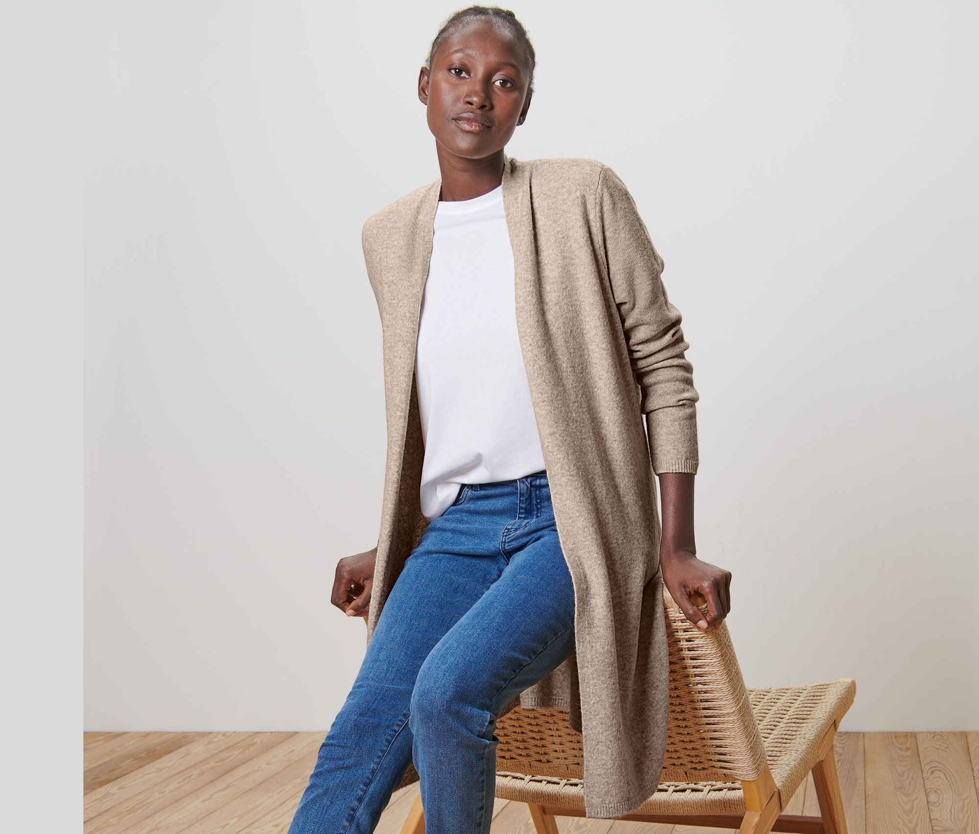 Frau sitzt auf einem Stuhl und trägt einen offenen Longcardigan.