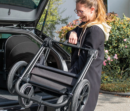 Frau hebt schwarzen Osann Kombi-Kinderwagen »Vamos« aus dem Kofferraum.