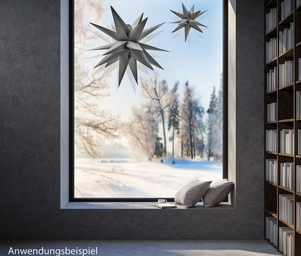 Zwei graue 27 cm AMARE LED-Sterne hängen vor einem Fenster mit Blick auf eine verschneite Landschaft.