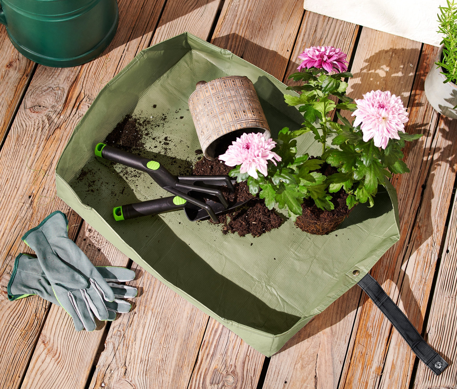 Pflanzmatte, Blumen und Gartengeräte auf Holztisch.
