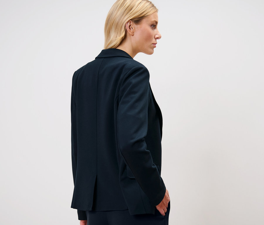 Blonde Frau trägt einen Jerseyblazer.