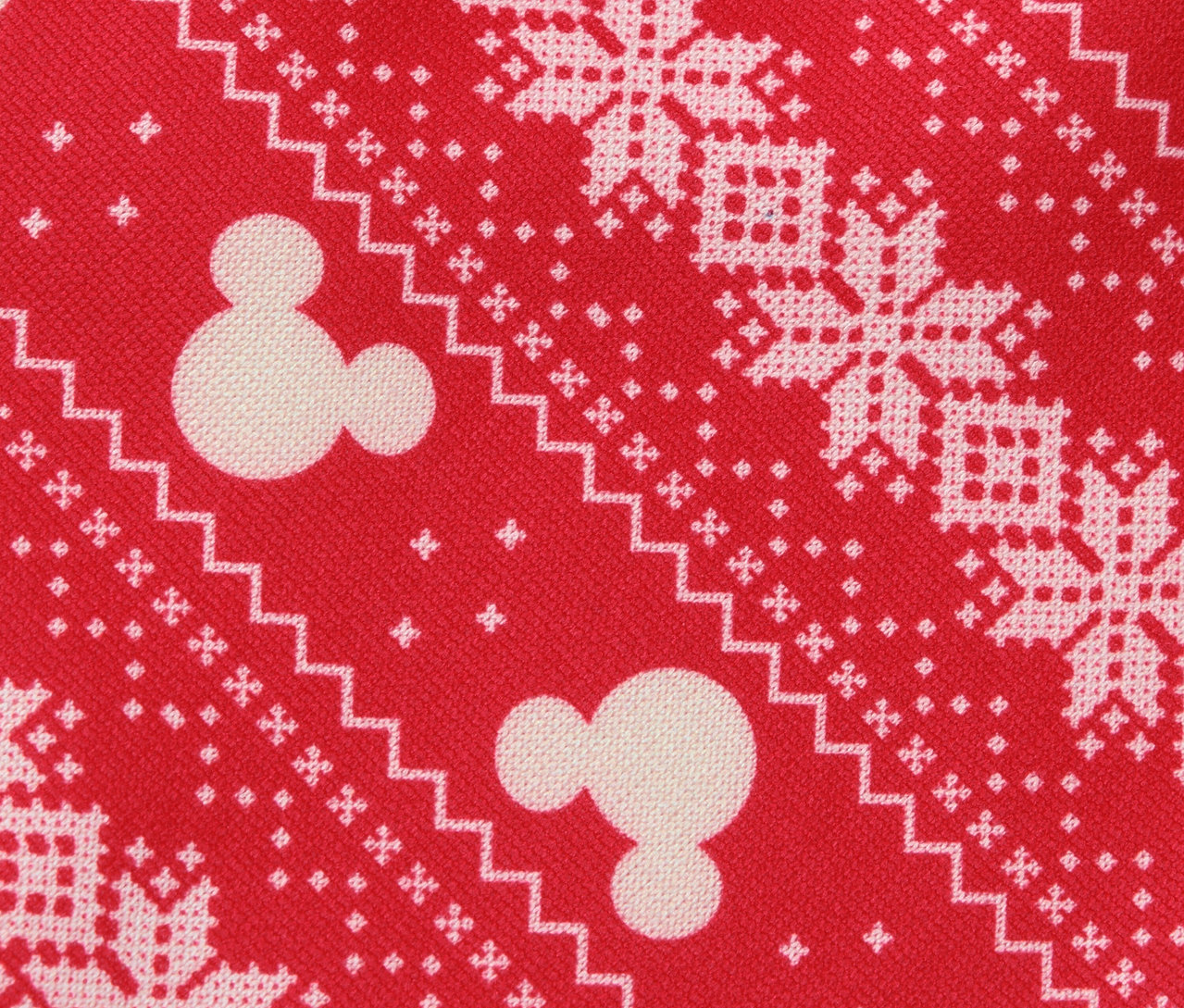 Gemusterte rote Stoffoberfläche mit weißen Schneeflocken und Mickey-Mouse-Motiven.