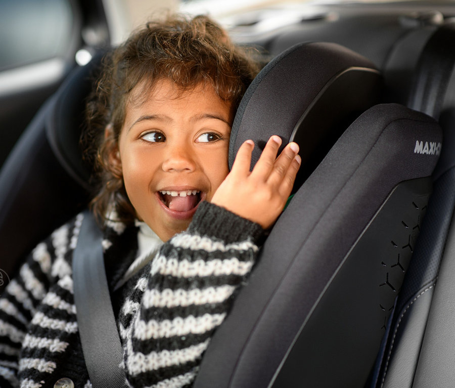 Lächelndes Mädchen sitzt im Maxi-Cosi Kinder-Autositz »Rodifix S«, i-Size.