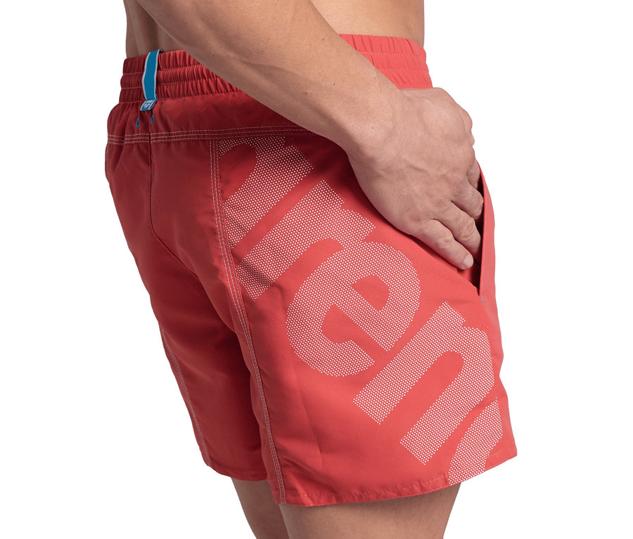 Mann mit Hand in der Tasche der roten Arena Pro_File Badeshorts.
