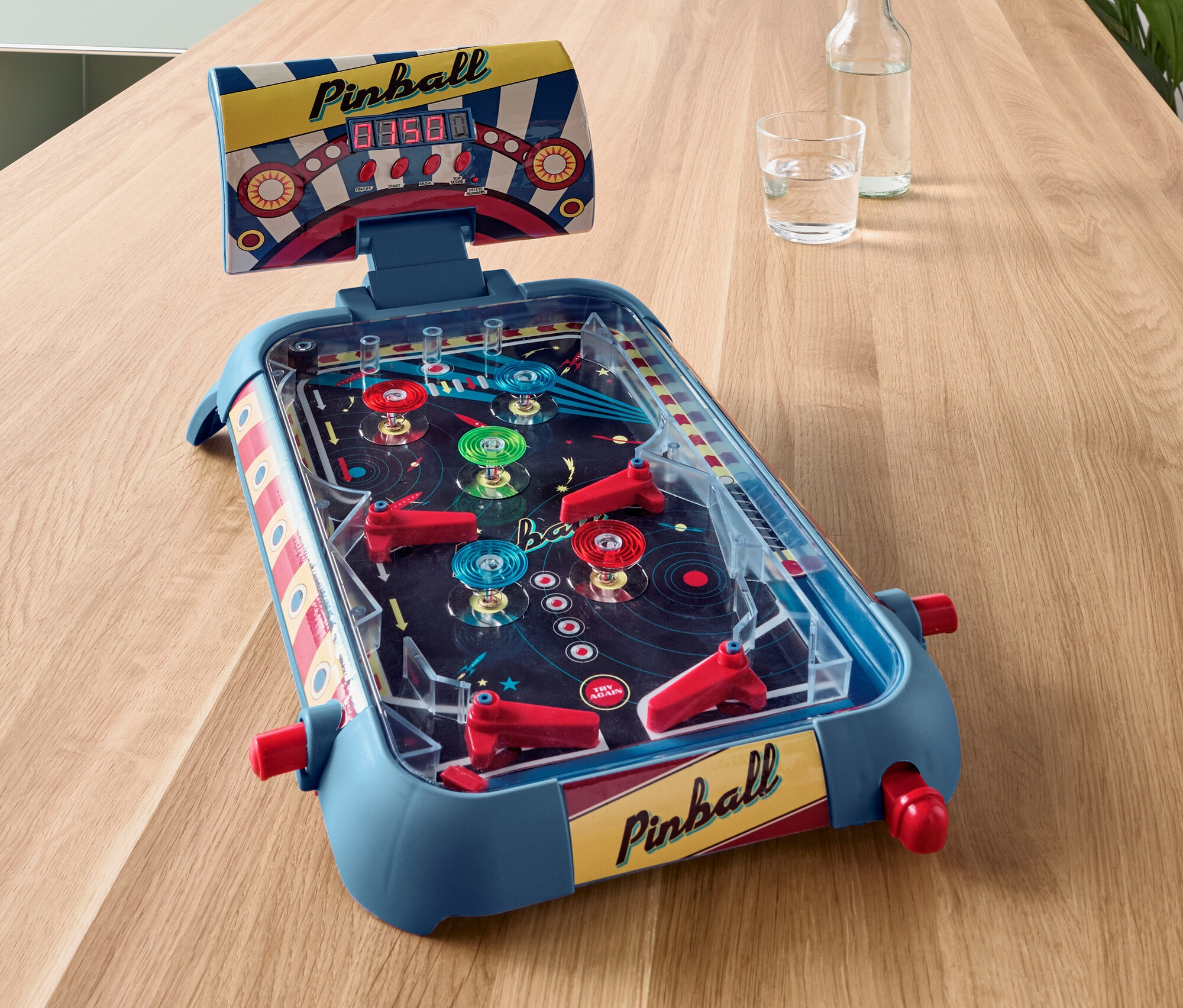 Ein blauer Mini-Flipper steht auf einem Holztisch.