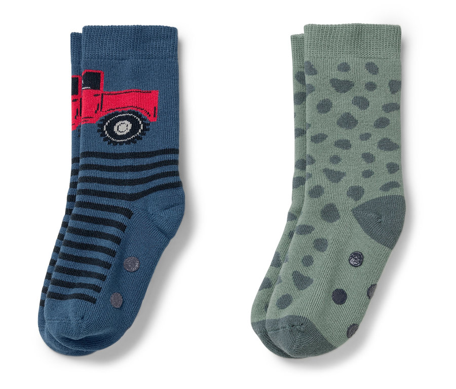 Zwei Paar Socken. Einmal blau mit rotem Lastwagen und Streifen, einmal grün mit dunkelgrünen Punkten.