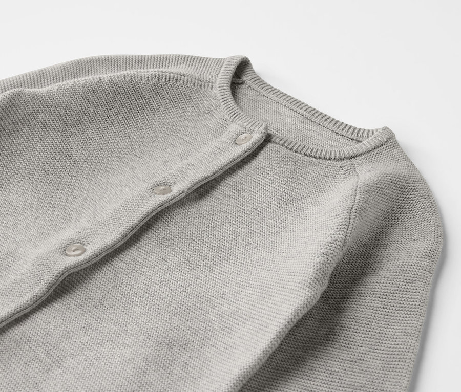 Detailansicht eines grauen Baby-Strickoveralls.