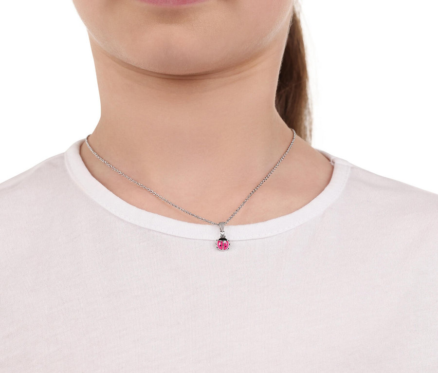 Junge Frau trägt eine silberne Halskette mit einem Marienkäfer-Anhänger vor einem weißen T-Shirt.