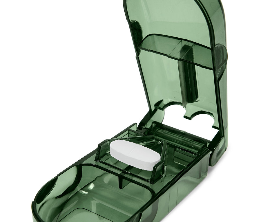 Eine weiße Tablette in einem geöffneten, durchsichtigen, grünlichen Tablettenteiler.