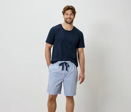 Mann mit blauem T-Shirt und gestreifter kurzer Hose.
