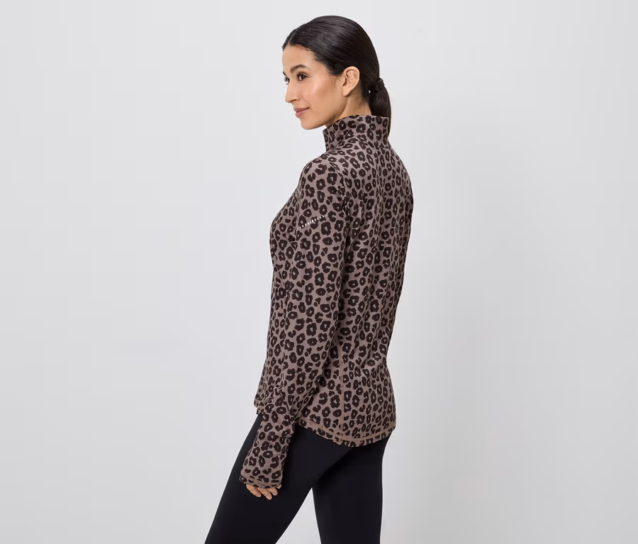 Frau im braunen, langärmeligen Leopardenmuster-Oberteil und schwarzen Leggings, seitliche Ansicht.