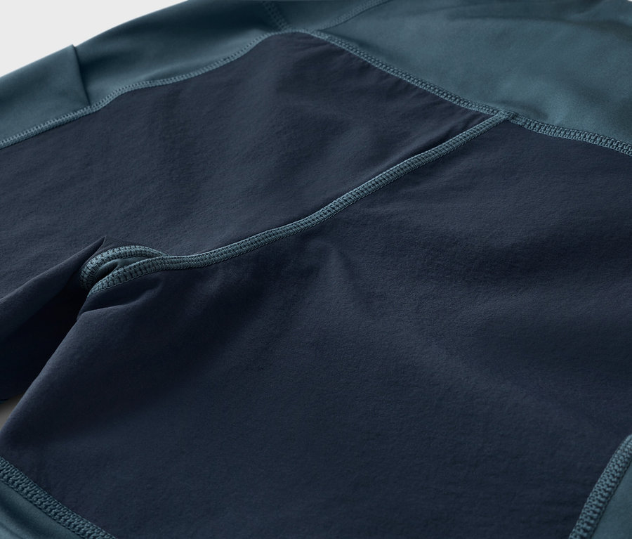 Nahaufnahme einer dunkelblau-grünen Hose mit dunkleren, quadratischen Einsätzen.