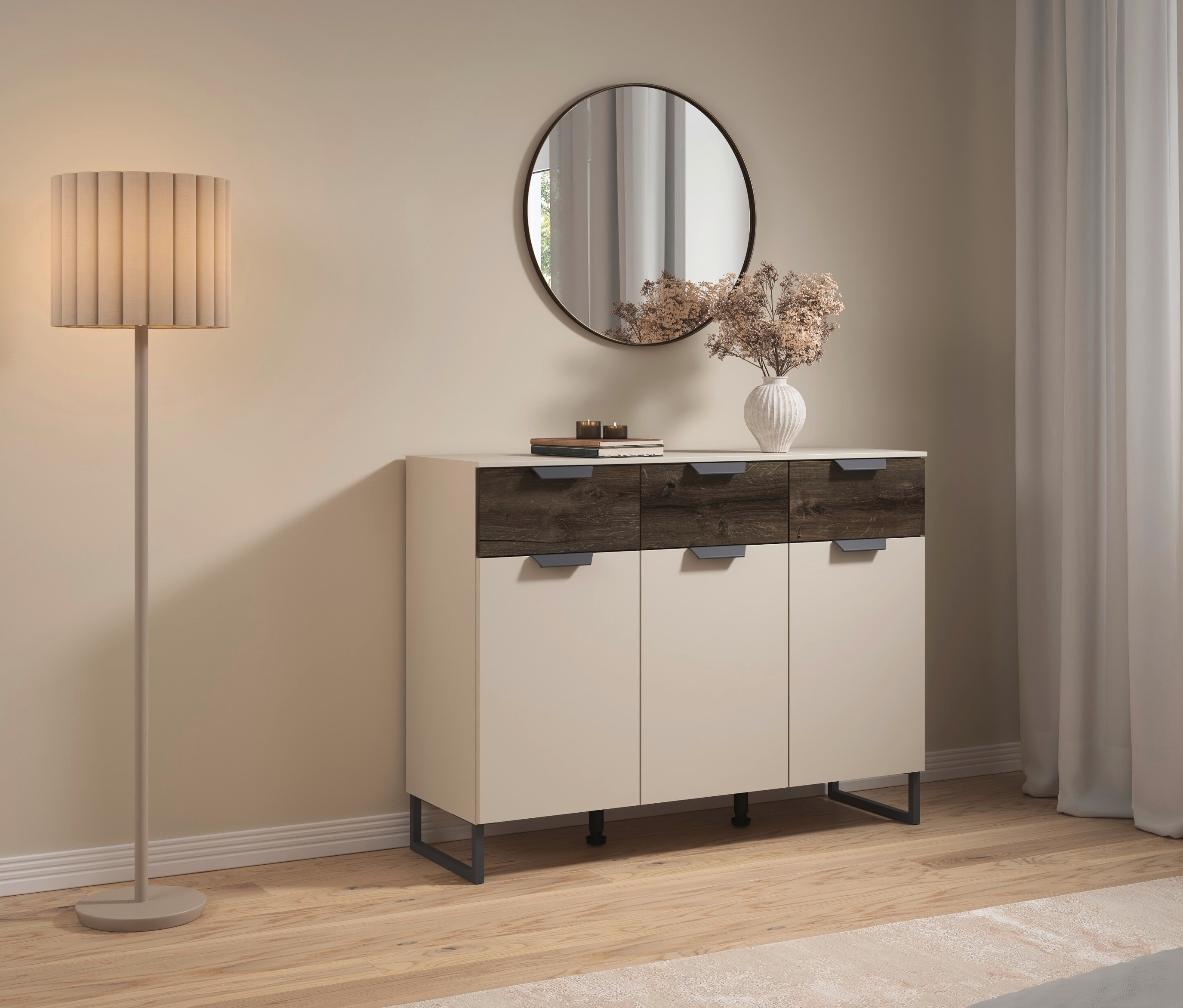 Stehlampe neben Kommode mit Spiegel darüber. Auf der Kommode stehen Bücher und eine Vase mit Blumen.