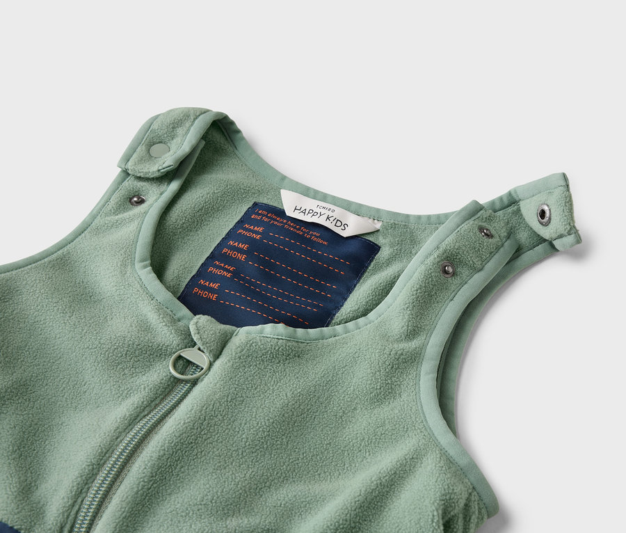 Nahaufnahme eines ärmellosen, hellgrünen Fleece-Schlafsacks mit Reißverschluss und Etikett mit Platz für Name und Telefonnummer.