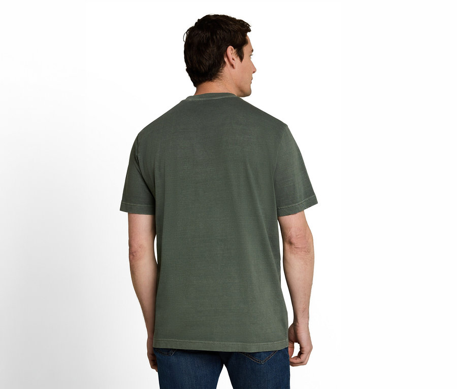 Ein Mann von hinten, der ein dunkelgrünes T-Shirt und blaue Jeans trägt und nach rechts blickt.