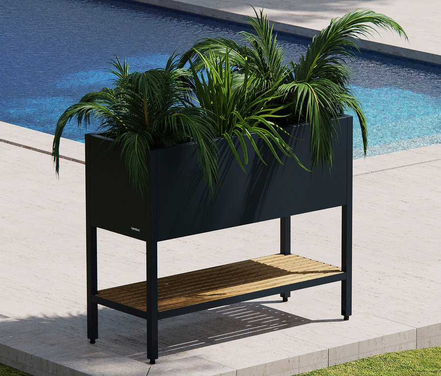 Schwarzer Pflanzkasten mit Pflanzen vor einem Pool.