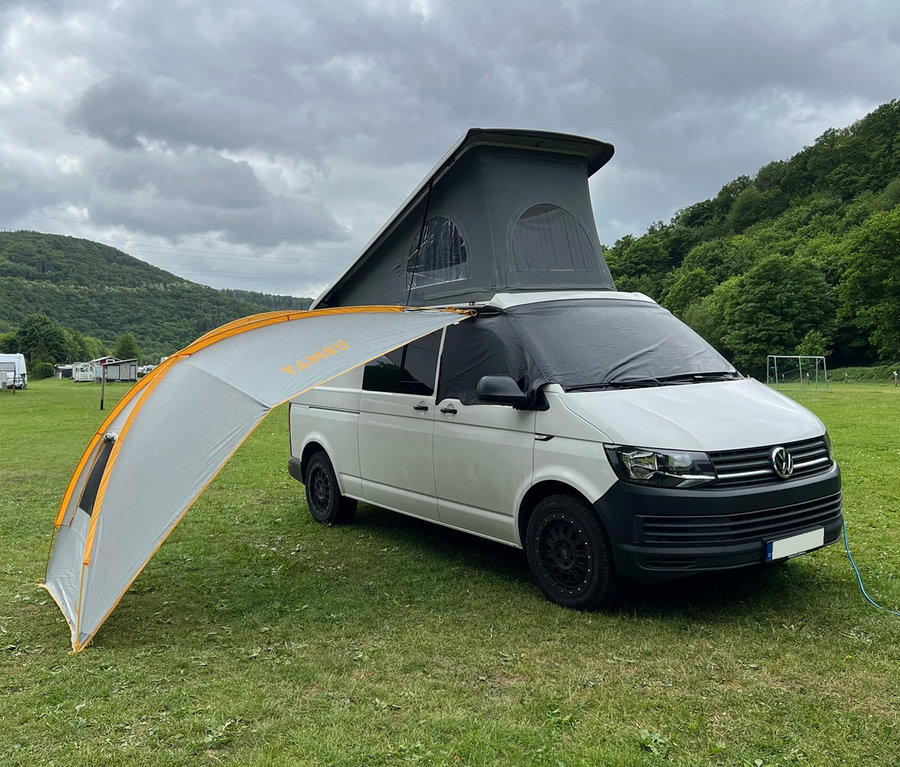 Weißer Van mit hochgeklapptem Dach und Tambu Sonnensegel »BASANT« auf einer Wiese.