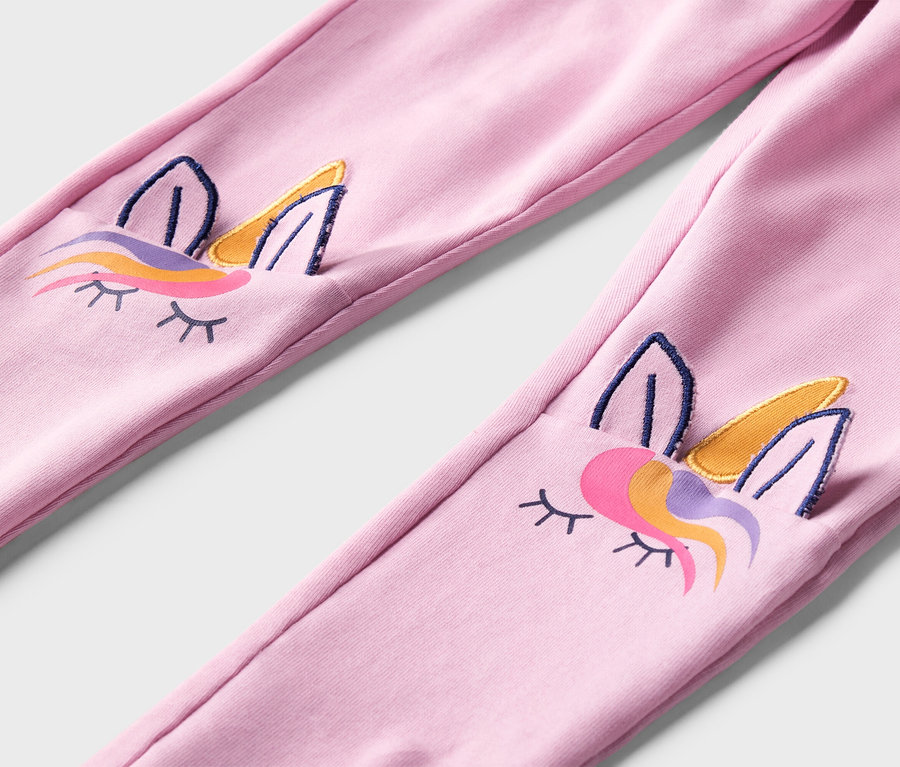 Nahaufnahme von rosa Leggings mit aufgestickten Einhorn-Gesichtern an den Knien.
