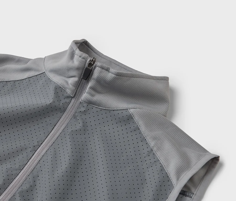 Nahaufnahme einer grauen Sportjacke mit Reißverschluss und perforierter Vorderseite.
