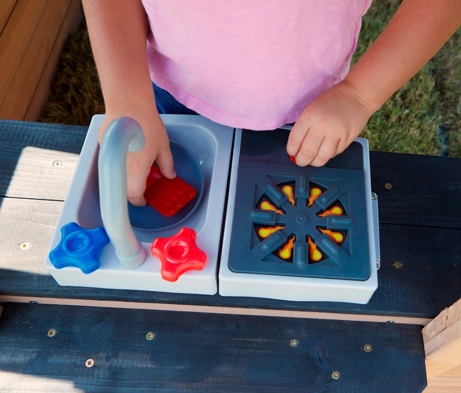 Kind spielt mit dem Spielhaus, Trolli, an Spüle und Herd.