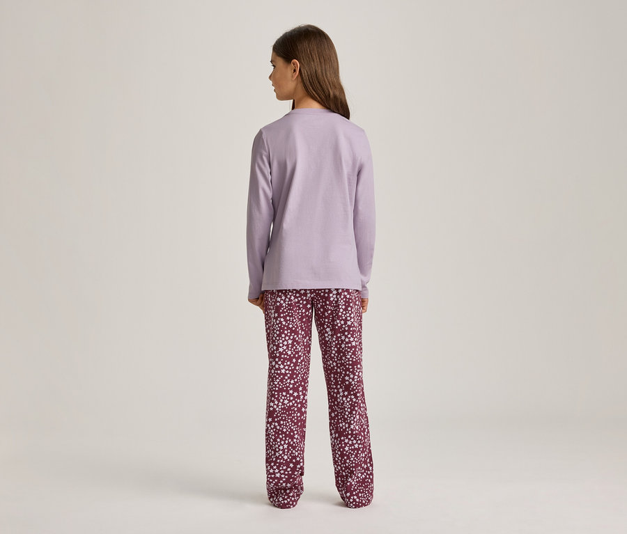 Eine Person steht mit dem Rücken zum Betrachter und trägt ein hellviolettes Langarmshirt und dunkelrote Hosen mit weißem Sternenmuster vor einem hellen Hintergrund.
