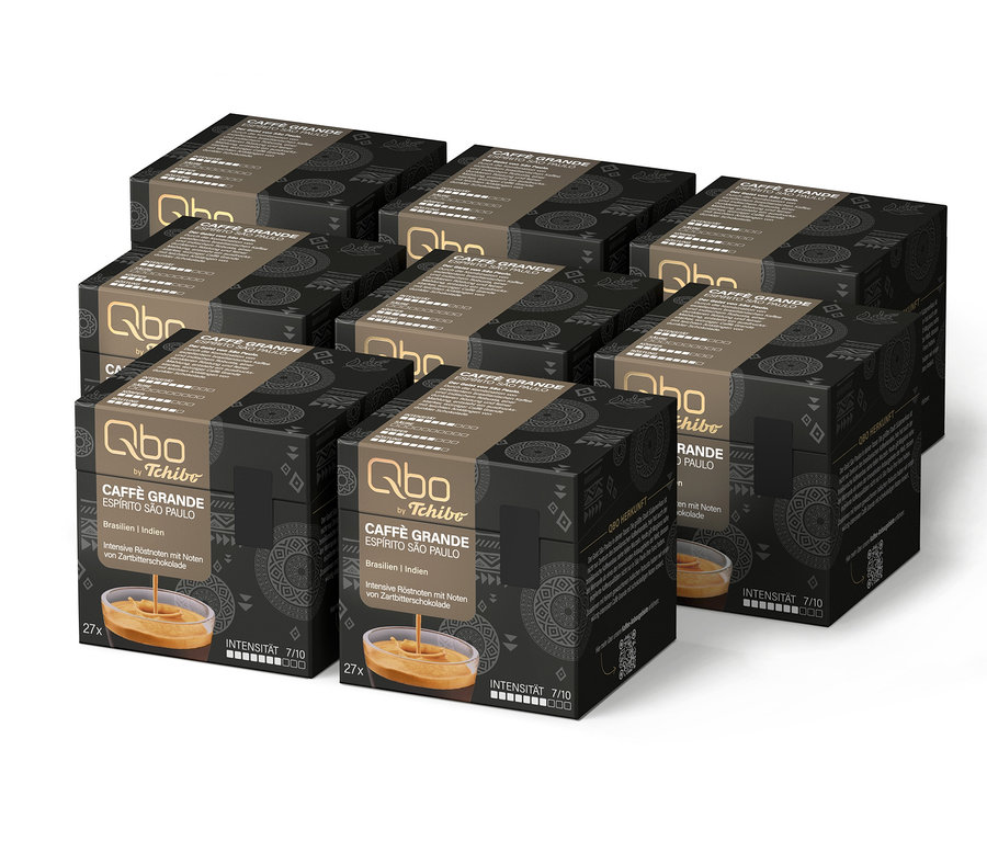 Sechs schwarze Schachteln Qbo Caffè Grande ESPÍRITO SÃO PAULO Kaffeekapseln von Tchibo, jede mit 27 Kapseln, Intensität 7/10 und Noten von Zartbitterschokolade, mit einem Bild von Kaffee in einem Glas.