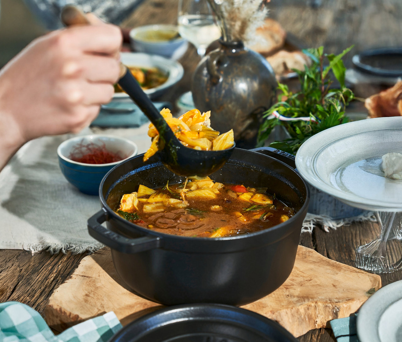 Eine Person schöpft mit einer Schöpfkelle eine Mahlzeit aus einer schwarzen STAUB »Cocotte 24« mit ca. 3,7 l.