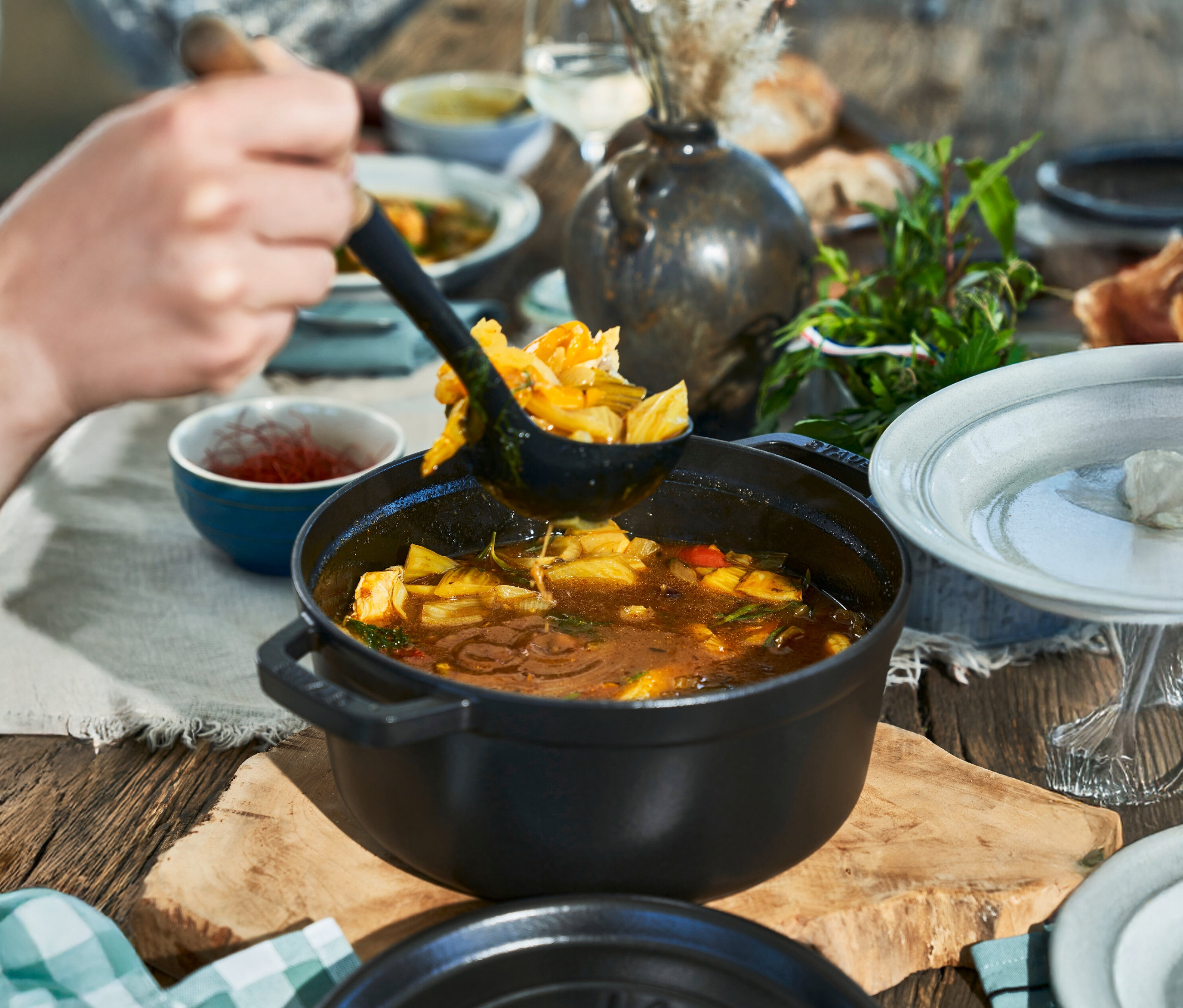 Eine Person schöpft mit einer Schöpfkelle eine Mahlzeit aus einer schwarzen STAUB »Cocotte 24« mit ca. 3,7 l.