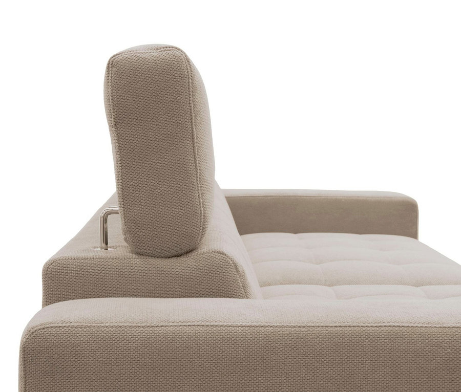 Nahaufnahme eines beigen Stoffsofas mit verstellbarer Kopfstütze. Das Sofa hat einen strukturierten Webstoff, eine niedrige Rückenlehne und eine breite Armlehne rechts. Die Sitzfläche ist leicht gesteppt, die Kopfstütze ist mit einer silbernen Metallhalterung befestigt.
