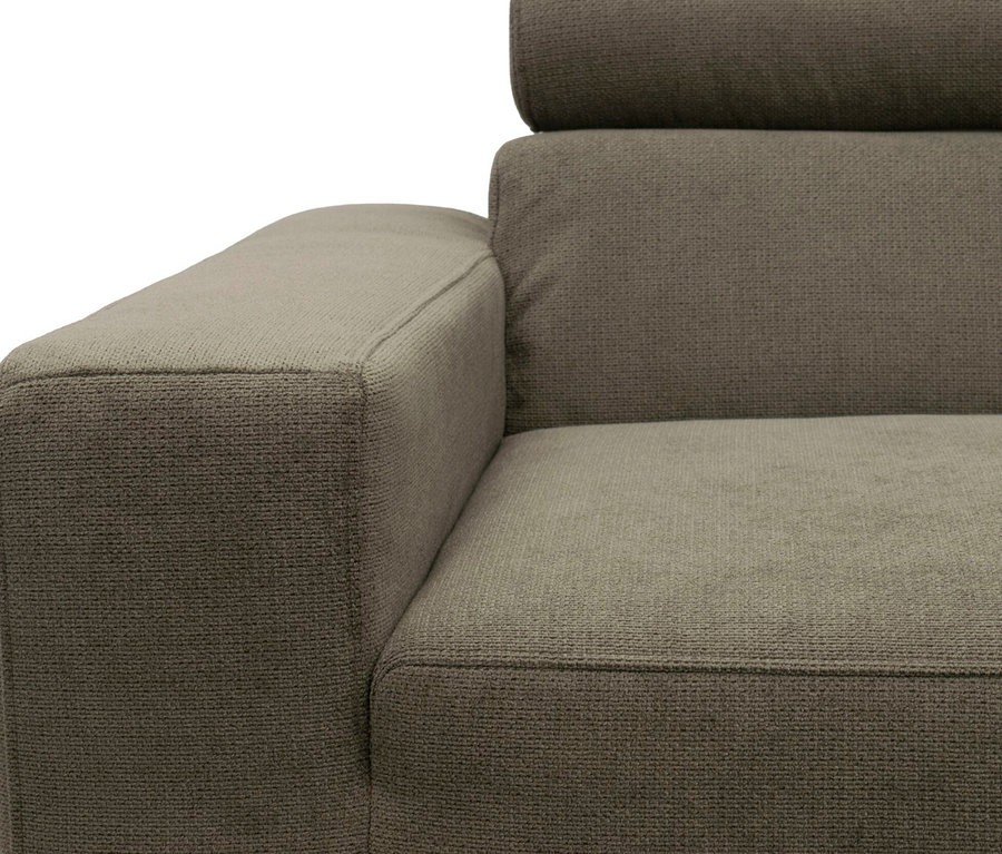 Nahaufnahme eines graubraunen Stoffsofas, das die Armlehne links, eine Rückenlehne und eine Kopfstütze zeigt. Der Stoff hat ein strukturiertes, gewebtes Muster.